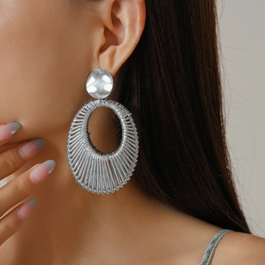 Detailed side view of model wearing woven mesh oval earrings with metallic silver finish