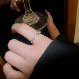 Detail of silver bow knot metal ring on finger with elegant minimalist wavy design