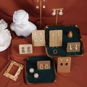 Golden earring set with pearls and tassels displayed on elegant jewelry stands