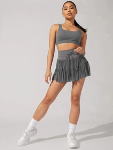 Detail of dark grey pleated sports skirt and matching cropped tank top on a model