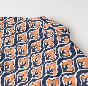 Close-up of quilted floral pattern vest in orange and navy blue with satin finish