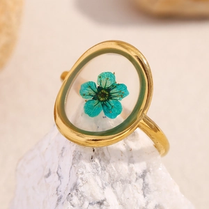 Detailed close-up of 18K gold-plated oval ring with real green dried flower in resin