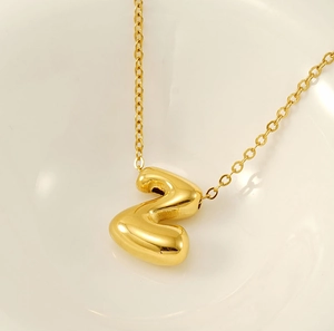 Macro detail of high-polished 18K gold plated bubble letter Z pendant on a cable chain