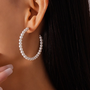 Close-up of elegant oversized C-shaped pearl hoop earrings worn on a model's ear
