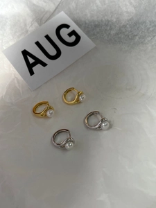 Macro detail of gold and silver huggie earrings with round white natural pearls