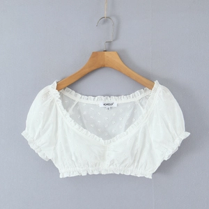 Dettaglio top corto in pizzo bianco con ricamo, scollo a V e maniche a sbuffo su gruccia
