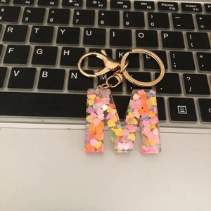 Macro detail of letter M keychain with colorful heart sequins on laptop keyboard