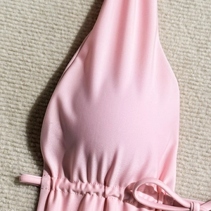 Close-up of pink pearlescent fabric texture and drawstring tie detail on a swimsuit