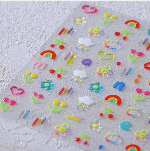 Macro view of 3D resin nail art stickers with colorful rainbows, hearts and cherry patterns