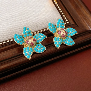Close-up of vintage flower earrings with blue turquoise-style beads and gold base