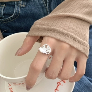 Close-up of a sterling silver irregular concave ring worn by a model holding a cup