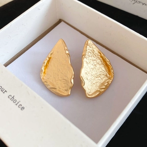 Detail of gold hammered teardrop earrings inside a minimalist white gift jewelry box