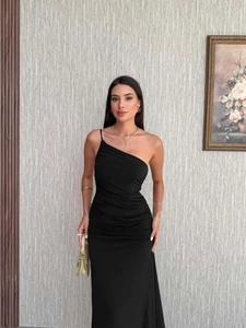 Detail of elegant black one-shoulder dress with slimming ruched waist and floor-length hem
