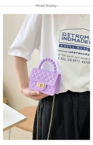Detail of purple quilted PVC jelly bag with gold hardware and beaded handle on a model