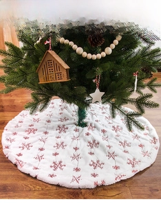Detail of white plush Christmas tree skirt with red sequin embroidered snowflakes