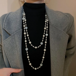Détail d'un collier élégant à double couche avec perles blanches et perles œil-de-chat bleues