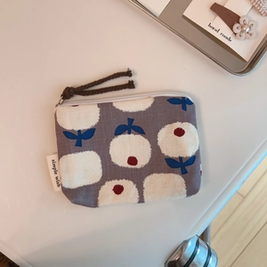 Close-up of canvas coin purse with floral pattern and simple wish woven brand tag
