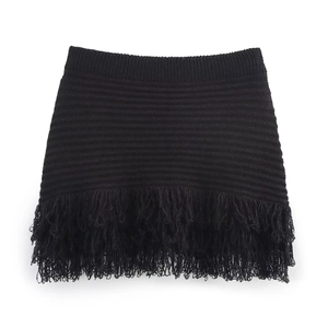 Detailed close-up of a black knitted high-waisted mini skirt featuring dense fringe hemline