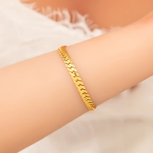 Detail of 18k gold plated stainless steel herringbone chain bracelet on female wrist
