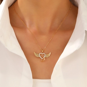 Close-up of golden angel wing heart pendant necklace with rhinestones on a female model