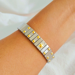 Close-up of stainless steel modular bracelet featuring a golden star and studs