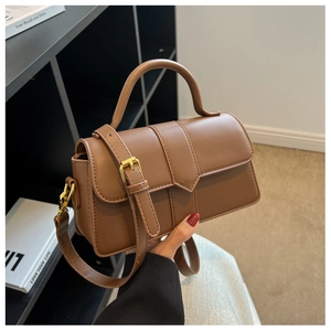 Detail showing the brown faux leather crossbody bag with elegant gold-tone hardware accents