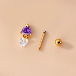 Detailed view of golden heart piercing studs with purple and clear zircon stones