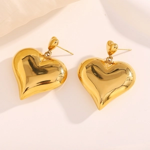 Detailed close-up of 18K gold-plated double heart drop earrings on a cream background