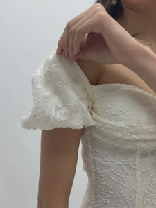Vue détaillée des manches bouffantes blanches avec texture 3D sur une robe longue élégante
