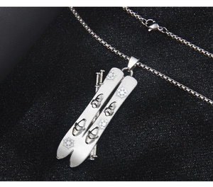 Detail of silver stainless steel snowboard and ski pole pendant with snowflake engraving