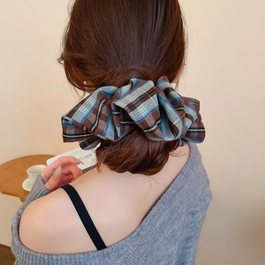 Close-up of blue and brown plaid fabric scrunchie styled on a woman's brown hair bun