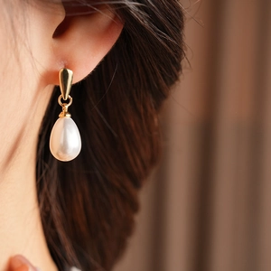 Close-up of model wearing French vintage teardrop pearl earrings with golden metal studs