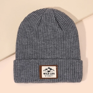 Grey ribbed knit beanie featuring an outdoor embroidery patch on a minimalist background