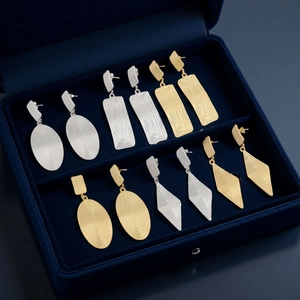 Irregular liquid metal heart and oval earrings in gold and silver finish on velvet box