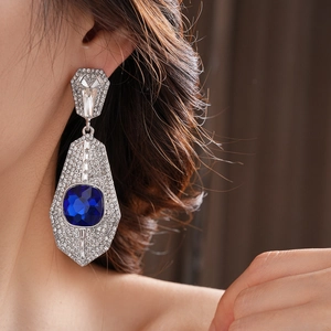 Detail of vintage geometric earrings with blue crystal stone and pavé diamonds on model