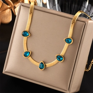 Detailed close-up of gold necklace with five blue teardrop stones on a gift box