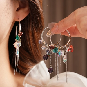 Détail de créoles argentées avec perles de cristal colorées et longues chaînes à glands