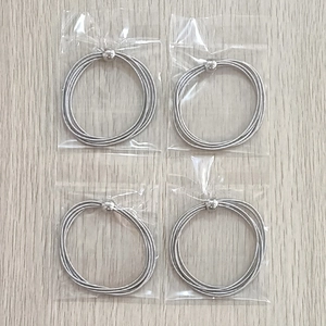 Macro detail of four silver stainless steel spring bracelets with small metal beads