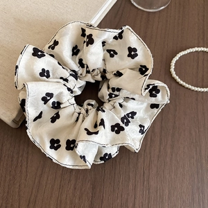 Detail of white floral silk scrunchie with black pattern on a vintage wooden table