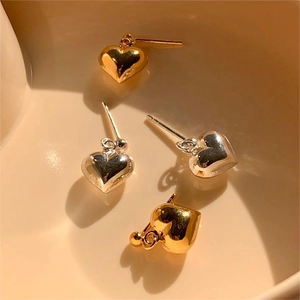 Close-up of gold and silver heart-shaped stud earrings in a decorative ceramic bowl