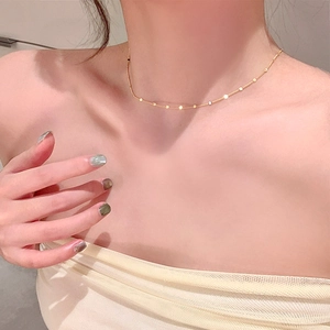 Gros plan d'un collier ras du cou doré à paillettes minimaliste avec un éclat élégant
