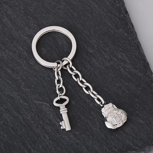 Detail of silver stainless steel keychain with luck bag charm on dark stone surface