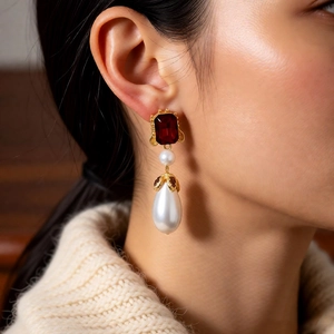 Macro shot of vintage gold drop earrings with red gemstone and white pearl detail