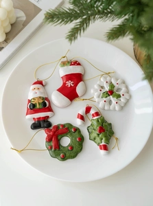 Detailed view of 5 ceramic Christmas ornaments including Santa, snowflake, and wreath