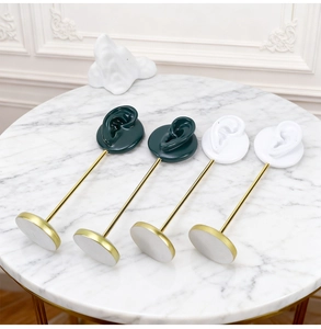 Detail of dark green and white resin ear display stands with gold metal rods on marble