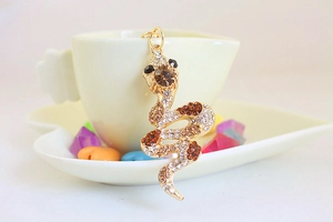 Close-up of golden snake pendant keychain with sparkling brown and clear rhinestones