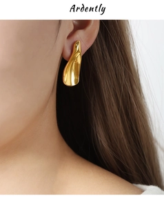 Close-up of modern abstract gold earrings on model showing minimalist curved texture