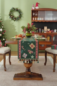 Detail of green Christmas table runner with festive gift box patterns and tassel fringe