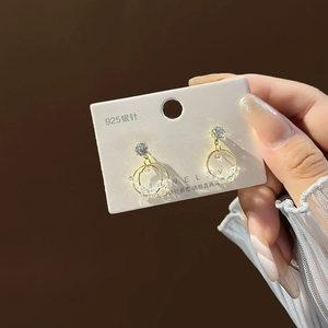 Close-up of geometric gold hoop earrings with white pearls and 925 silver needles