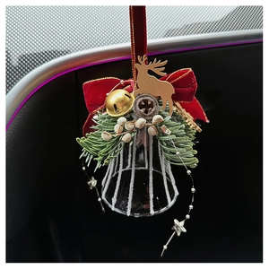 Close-up of a Christmas bell ornament with a red velvet bow and golden reindeer detail